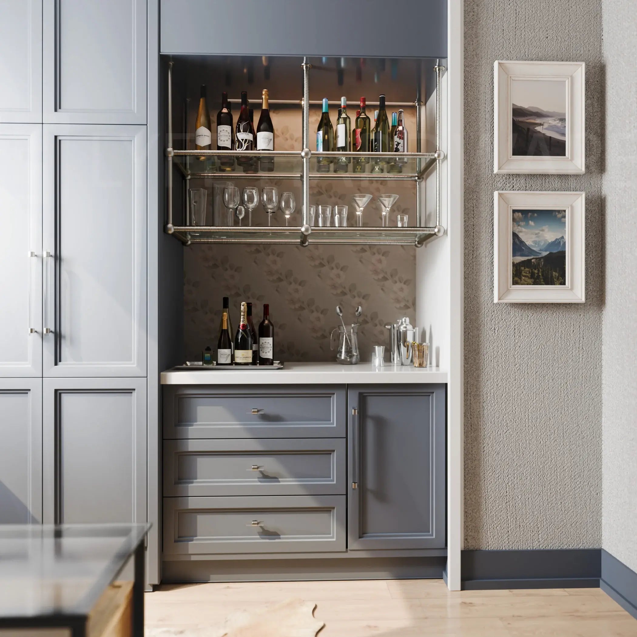 A sophisticated built-in home bar station featuring slate gray custom cabinetry, white countertop, and polished metal open shelving stocked with wine, liquor bottles, and various glassware, set against a subtle botanical print backsplash.